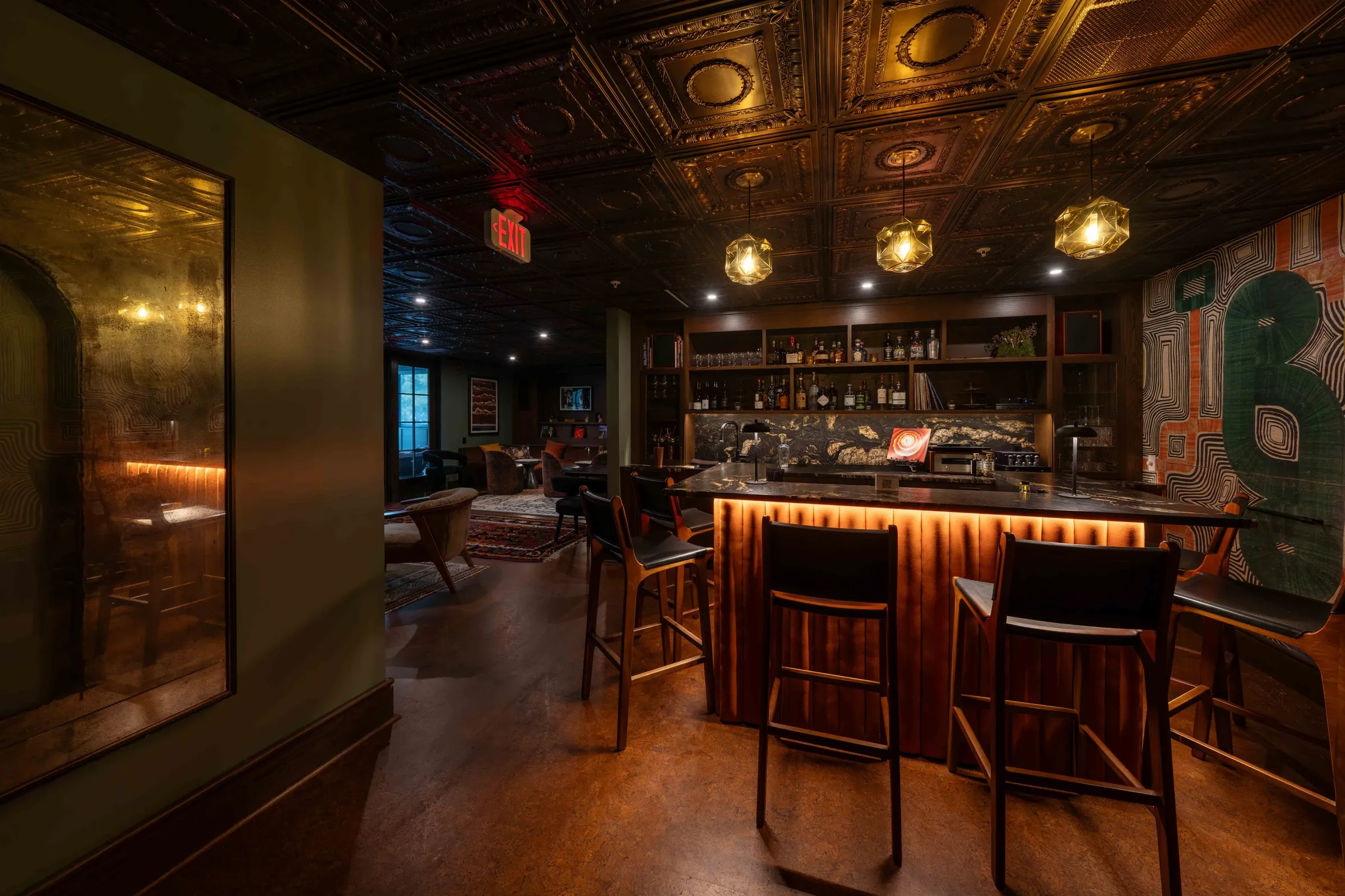 The bar in The McCabe Lounge, lit from below, with stools, pendant lights, and a pressed tin ceiling