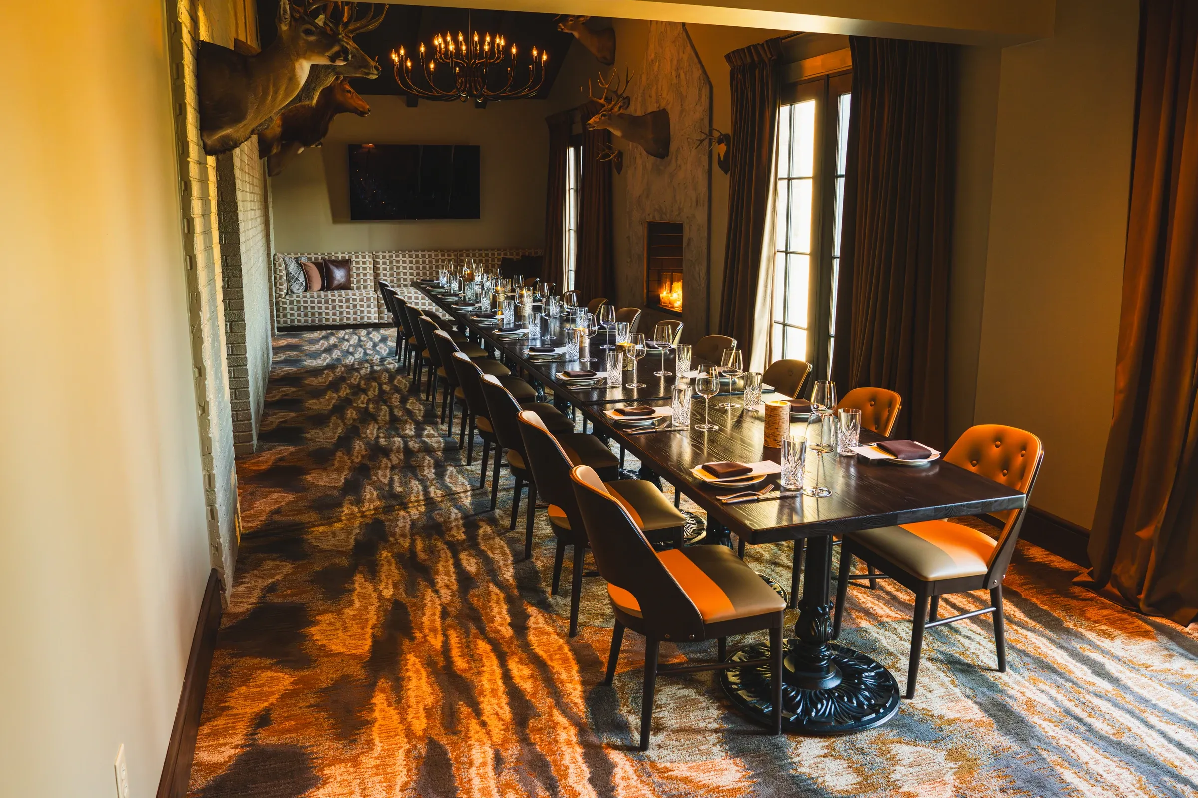 The long table in The Stag Room set with glasses, leather chairs on a patterned carpet